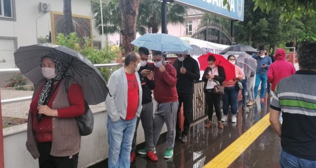 PTT önünde yağmur altında sosyal mesafesiz maaş kuyruğu