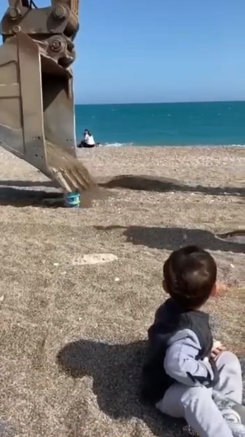 Sahilde oynayan minik çocuğun kum kovasını iş makinesi doldurdu